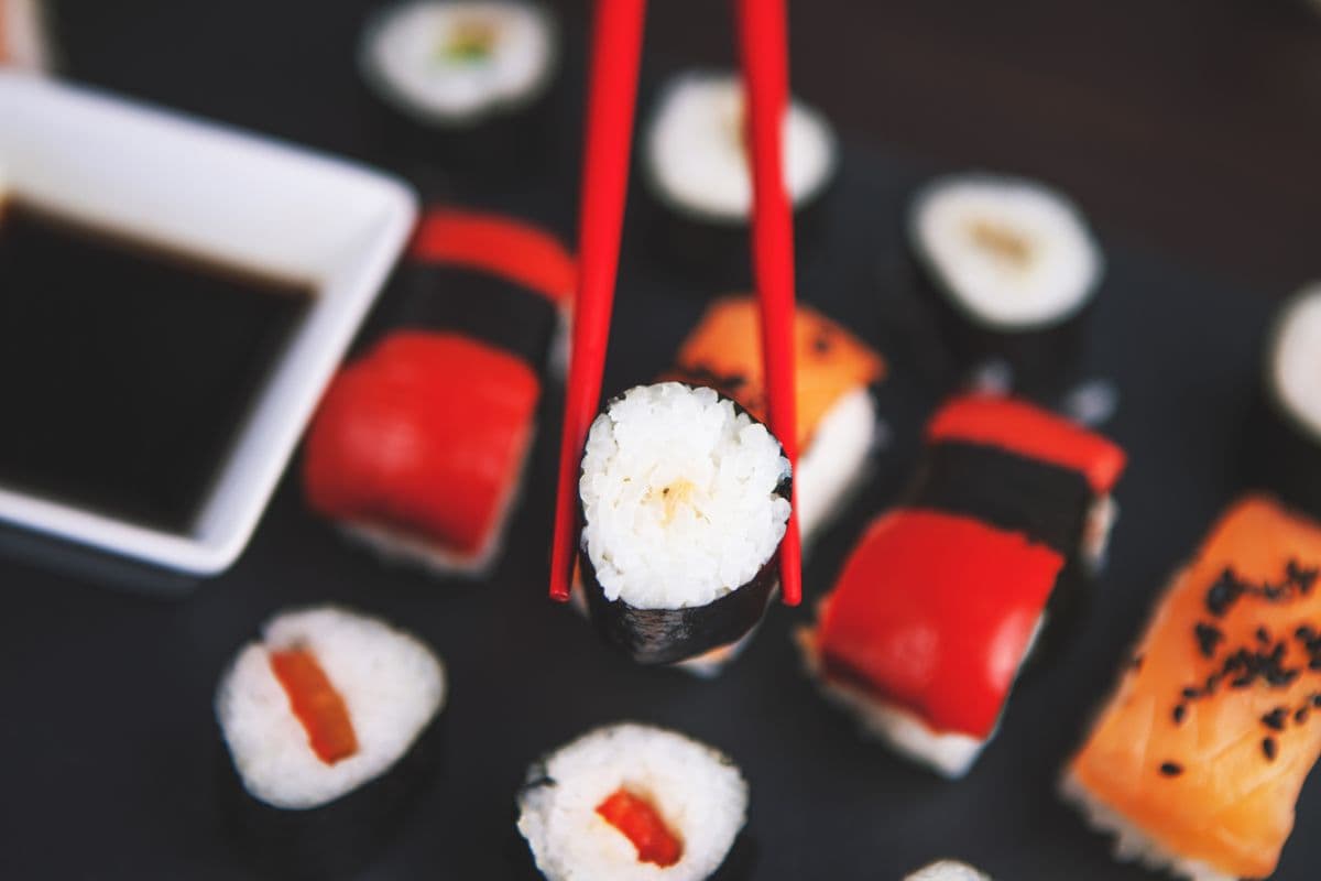 Rolky a nigiri na tmavom tanieri s paličkami.
