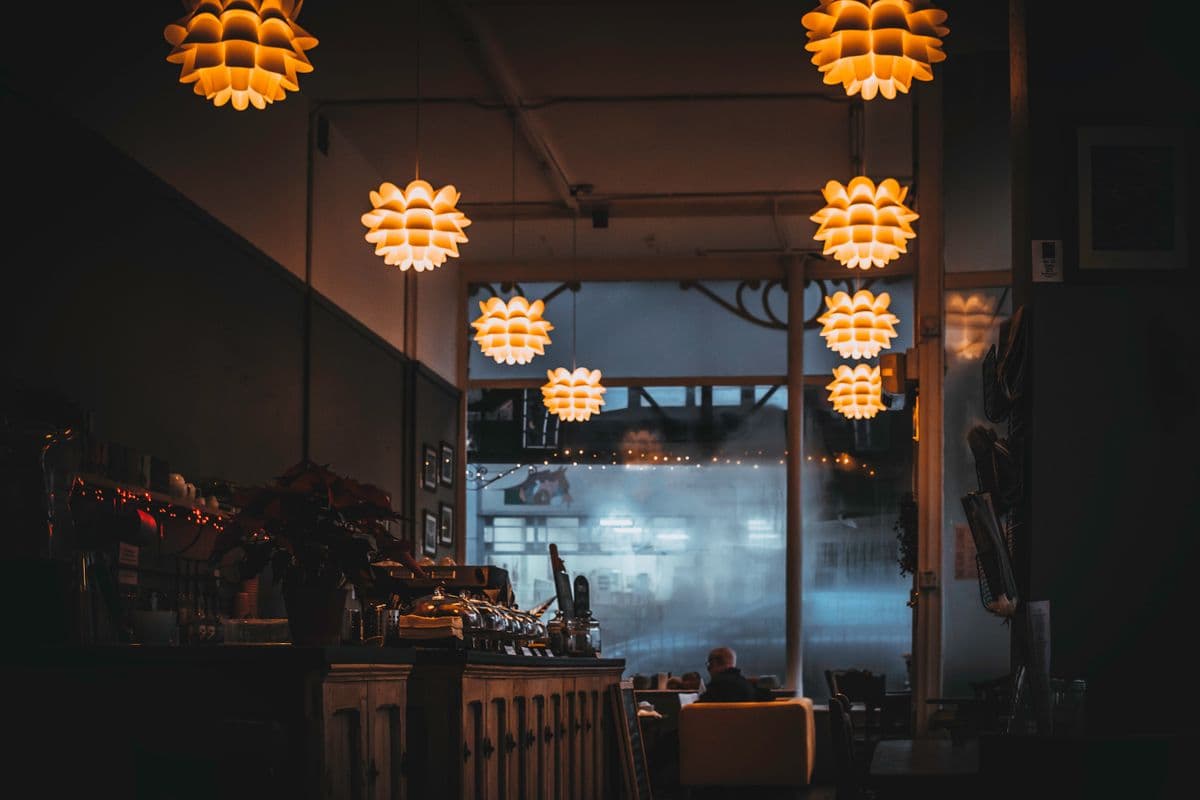Interiér reštaurácie za tmy — tmavé drevo, teplé lampy nad stolmi.